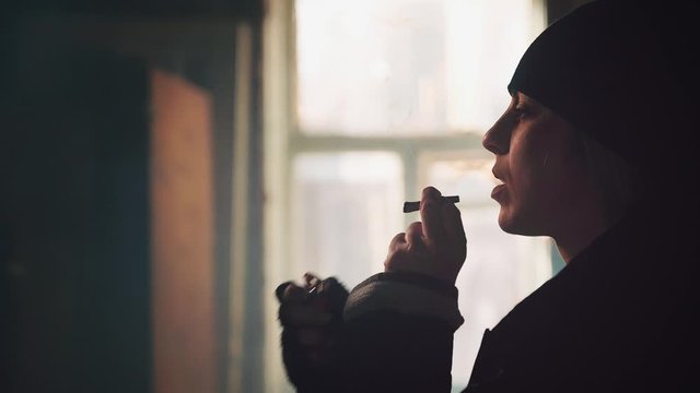 Addict young woman with a cigarette. Drug use, addiction, social degradation and self-destruction concept 