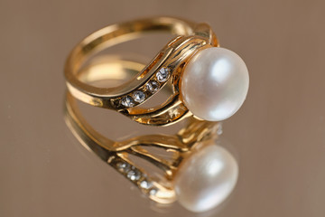 Golden ring with pearls on a glass table.