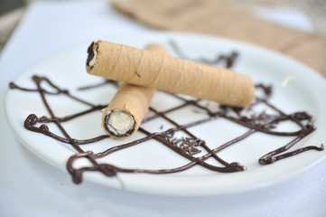 Fototapeta na wymiar Wafer roll with condened milk. Coffee desserts. Delicious dessert with coffee.