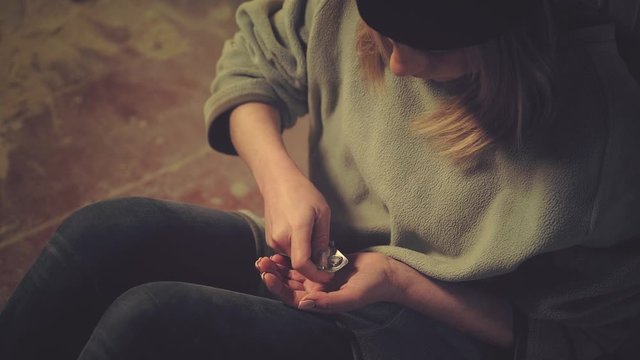 Unhappy young woman addict wants to eat pills in an abandoned house. Medicine and poison. Drug use, addiction, social degradation and self-destruction concept 