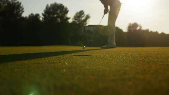 Golfer striking ball during sunset