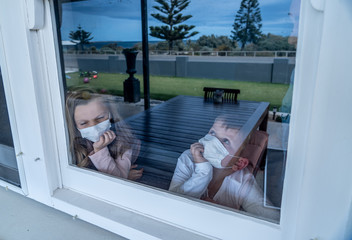 COVID-19 Quarantine. Sad little girl looking through the window feeling lonely during lockdown