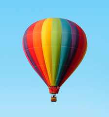 Rainbow colored hot-air balloon floating against a blue sky