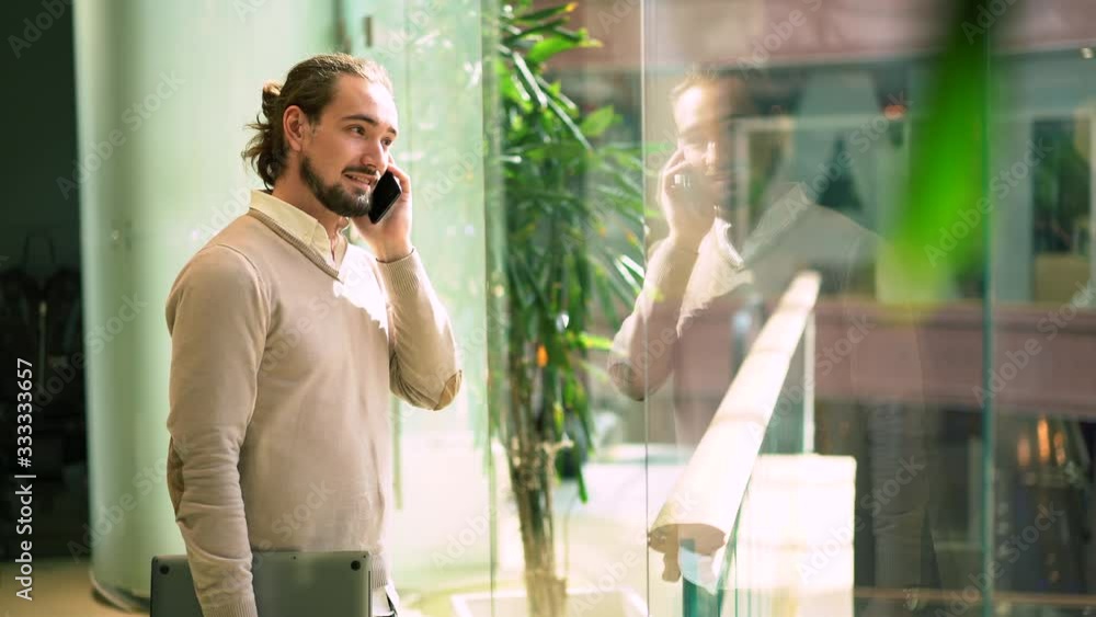 Poster caucasian marketer in smart casual clothing using smartphone application for calling and talking abo