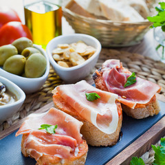 Spanish cuisine tapas with Serrano Ham and tomatoes - montadito de tomate y jamon serrano.