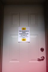 A self isolating residence with a quarantine sign on the front door warning of the Covid-19 virus.