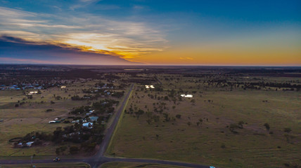 Aerial view during sunrise over the Australian outback near the village of Roma, Queensland, Australia. A drone view of the rising sun over the open flat landscape at dawn. 