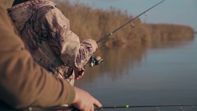 Fishermen catch predatory fish from a boat on a river in slow motion closeup