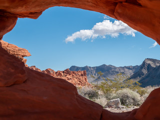 The desert view through a natural hole in red rock at Valley of Fire State Park, Nevada, USA.