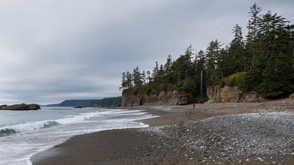 Distant backpacker hiking along the beach on the West Cost Trail on Vancouver Island, British Columbia, Canada