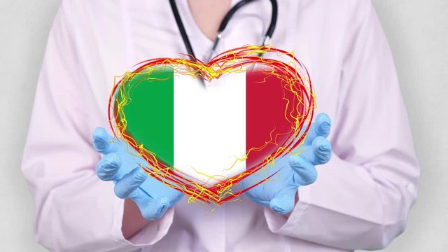 close-up. Doctor in medical white coat, blue gloves holds in hands drawn pulsating heart with Italy flag. Concept of doctors struggling against global epidemic, coronavirus.
