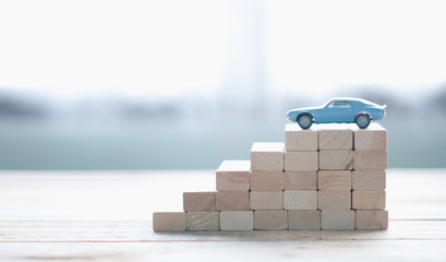 Arrange the wooden blocks stacked into steps. The ladder of career path concepts for the process of successfully saving money on car purchases
