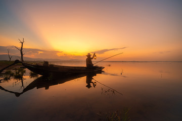 Picture of Asian fishermen on a wooden boat Thai fishermen catch fresh water fish in the natural river, traditional Thai fishermen at the morning sun on the lake of Thailand