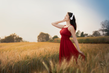 Obraz premium young woman listing the music in the barley farmland.