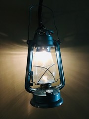 Ancient storm lantern hanging decorative on wall, light turn on in night