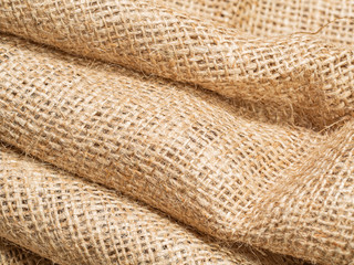 Close up view on brown crumpled burlap textile. Abstract background of brown sackcloth. Texture of brown burlap fabric. Selective soft focus. Blurred background