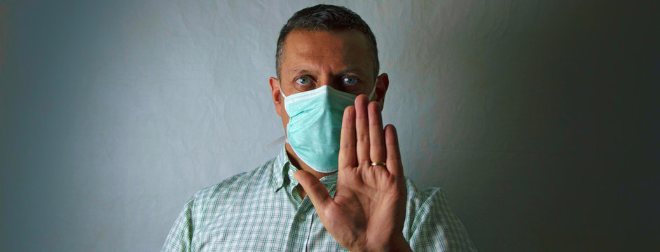 Hombre con mascarilla y su mano haciendo la señal de parar por coronavirus