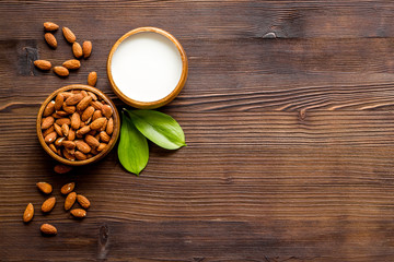 Almond milk near nuts on wooden background top-down copy space