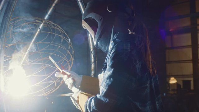 Talented Emerging Female Artist is Welding an Abstract, Brutal Metal Sculpture that Reflects the Present Moment. Beautiful Tomboy Fabricator in Checkered Shirt Creating Modern Steel Art.