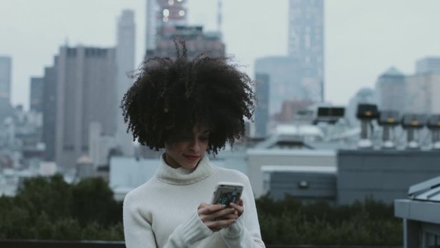 Afro American female on mobile phone on rooftop in Manhattan New York