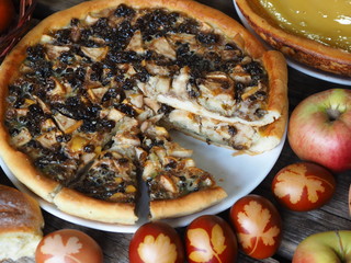 A round sweet cake with nightshade berries and apples covered with beaten eggs on the festive Easter table with eggs.We welcome guests of friends.