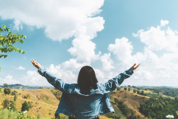 Woman raise hand up at top of mountain on blue sky and white cloud abstract background.