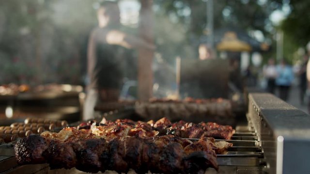 Shish kebabs preparing on skewers outdoors. Chef male cooking meat outside