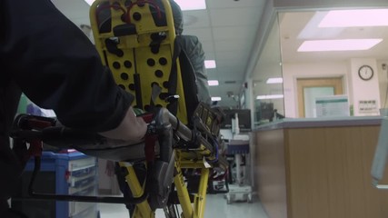 EMT (Emergency Medical Technician) pushes ambulance stretcher / gurney through Hospital Emergency Room. Slow Motion - 4K UHD - Powered by Adobe