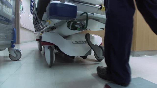 Emergency Room Nurse pushes stretcher / gurney down Hospital Emergency Room hallway. Camera follows in slow motion - 4K UHD