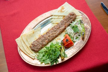 Traditional oriental Adana kebap and shashlik skewer with tomato and flatbread stock photo