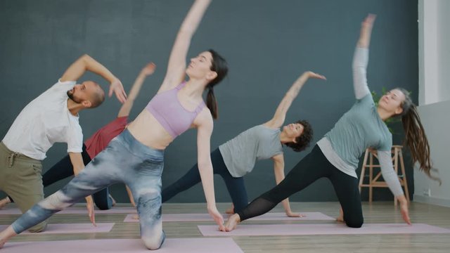 Yoga class women and man are doing exercises then relaxing sitting on mats with hands in namaste. Active lifestyle, healthy youth and recreation concept.