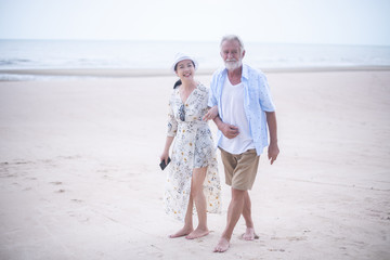 Retired couple walking on the beach.happy senior man and woman  holding hands together with love...