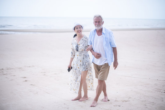 Retired couple walking on the beach.happy senior man and woman  holding hands together with love and care in romantic mood.Positive relationship of old people concept