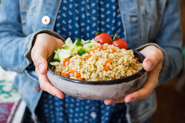 Vegetable bulgur pilaf or pulao. Woman holds in hands turkish  or Levantine Arabic durum wheat cooked grain as part of vegan, vegetarian healthy  diet food.