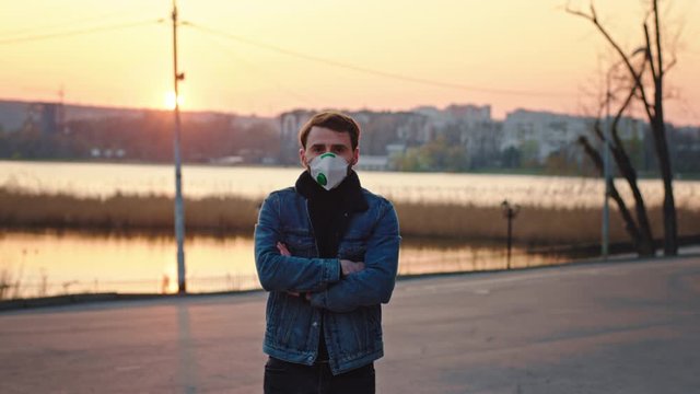 Good looking man standing in front of the camera he looking at sunset in the empty park he wearing protective mask concept of healthy and safety life Covid-19