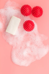 Coronavirus prevention. Soap and foam near virus model on pink background top-down