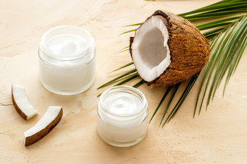 Face care. Coconut cream in glass jar on beige background