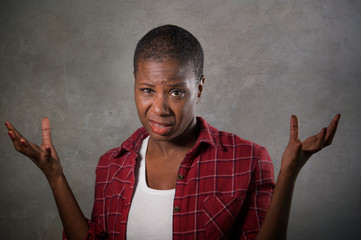 young unhappy and upset black African American woman with head shaved feeling frustrated and stressed isolated on dark background looking at camera in desperate gesture