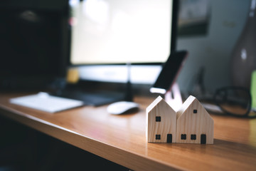 Wooden house model on workplace table background in work from home concept.