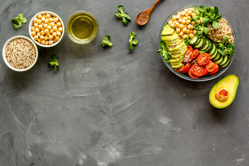 Healthy salad bowl with quinoa, avocado and chickpeas on grey background top-down copy space