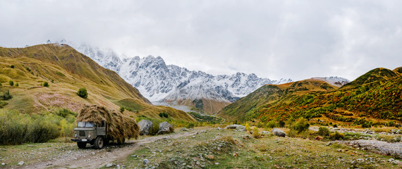 Fantastic golden autumn landscape between the rocky mountains in Georgia. Snow on the tops. orange. yellow. green grass. Beautiful view to the rock. 