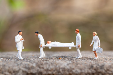 Miniature people : Doctor with nurse carry the patient on a stretcher.