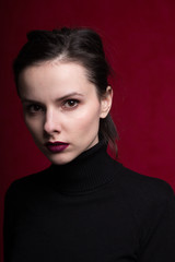 girl with red lipstick on the lips in a black turtleneck, red background