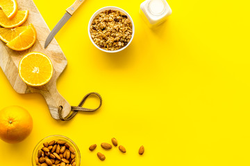 Morning granola near toast and oranges on yellow background top-down frame copy space