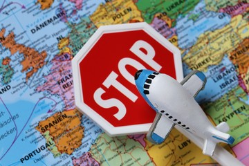 Airplane Traffic Limitations. Air traffic stopped.Air travel prohibited.Ban on air travel.Coronavirus epidemic problem. Decorative airplane and stop sign on world map background.Flying on a plane Ban