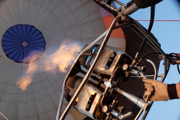 the hand holds the lever that releases the fire from the burner into the dome of the balloon