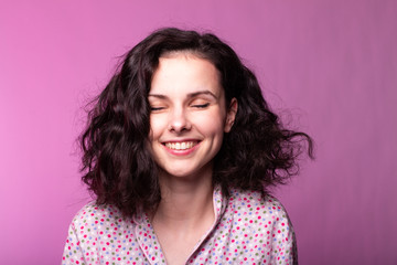 beautiful curly girl in pajamas, pink background