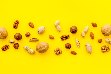 Nuts background - with almond, macadamia, walnut, hazelnut, pecans - on yellow table top-down copy space