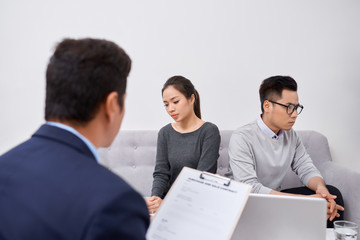 Young angry couple of cheated investors holding papers arguing with male real estate agent, defrauded property purchasers protecting their rights, too high interest rate of banking loan or mortgage