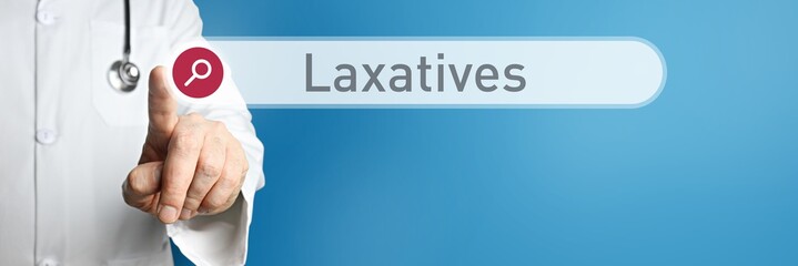 Laxatives. Doctor in smock points with his finger to a search box. The word Laxatives is in focus. Symbol for illness, health, medicine